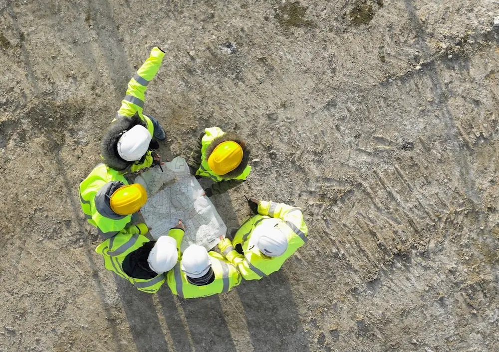 Photo d'un groupe d'ouvrier, communiquant autour d'un plan de chantier, illustrant l'esprit d'équipe au sein de l'entreprise NC Prefa